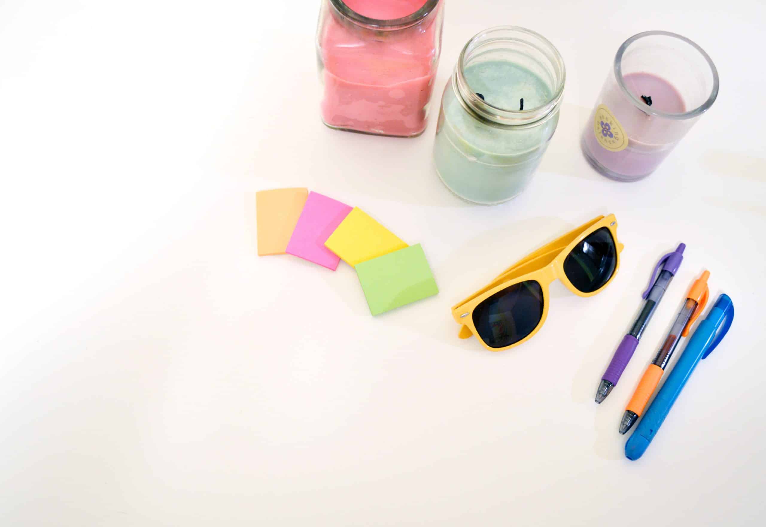 goodies sur fond blanc lunettes de soleil post it bougies stylos